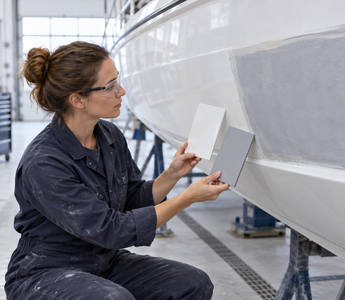 Woman comparing a polished gelcoat panel with a rolled marine paint finish on a boat