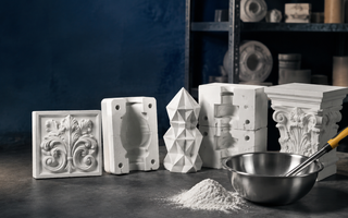 Premium casting studio with plaster reliefs, multi-part moulds, architectural ornament, a geometric gypsum casting, mixing bowl and white gypsum powder.