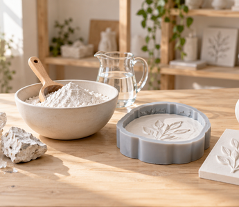 Natural gypsum crystals, plaster powder, water, a silicone mould and finished white plaster castings on a maker’s worktable.