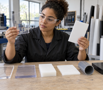Woman comparing labelled samples of acrylic, polycarbonate, polyethylene and polypropylene