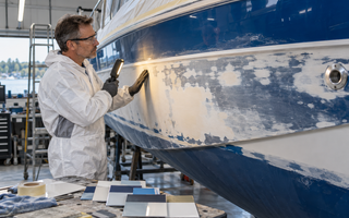 Woman inspecting a sanded fibreglass boat hull before choosing paint or re-gelcoat