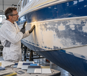 Woman inspecting a sanded fibreglass boat hull before choosing paint or re-gelcoat