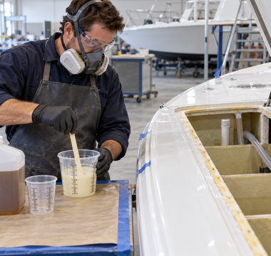 Marine technician mixing a controlled batch of two-part polyurethane foam beside a vented boat flotation cavity