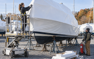 Woman shrink-wrapping a boat with marine film in a controlled outdoor work area