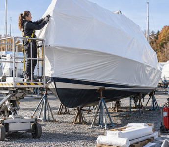 Woman shrink-wrapping a boat with marine film in a controlled outdoor work area