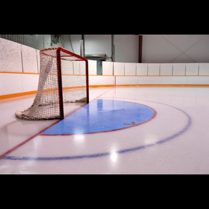 An indoor hockey rink with a goal net, ice surface, and white HDPE arena boards.