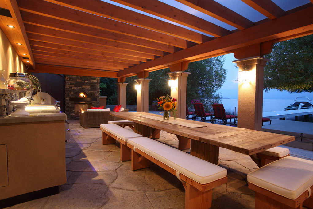 Timber dining table beneath clear multiwall polycarbonate roofing overlooking Okanagan Lake